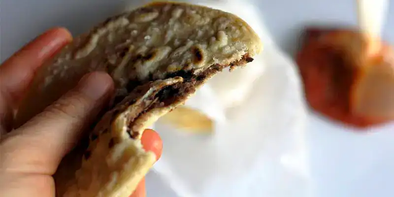 Chalupa mexicana tradicional con carne, queso y ingredientes frescos, ideal para disfrutar en desayunos o meriendas.