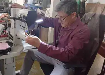 Soldador trabajando en taller de reparación y manufactura de maquinaria industrial en un ambiente de taller mecánico, enfocado en empleo y servicios para migrantes, en el contexto de SoyMigrante.com REVISTA.