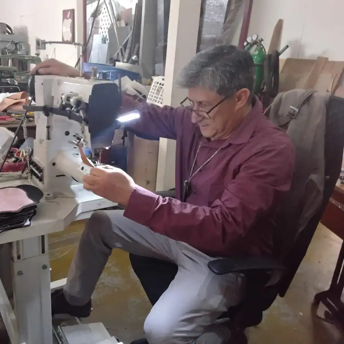 Soldador trabajando en taller de reparación y manufactura de maquinaria industrial en un ambiente de taller mecánico, enfocado en empleo y servicios para migrantes, en el contexto de SoyMigrante.com REVISTA.
