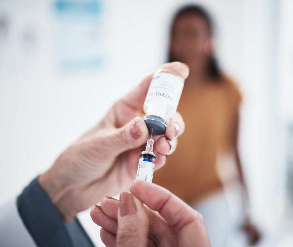 Vacuna COVID-19 siendo administrada por un profesional de la salud en un entorno clínico. – SoyMigrante.com REVISTA