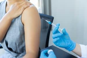 Vacuna contra el COVID-19 administrada a una persona, énfasis en salud y vacunación. – SoyMigrante.com REVISTA