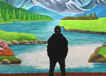 Paisaje pintado de montañas, río y naturaleza con persona observando mural artístico en la revista SoyMigrante.com.