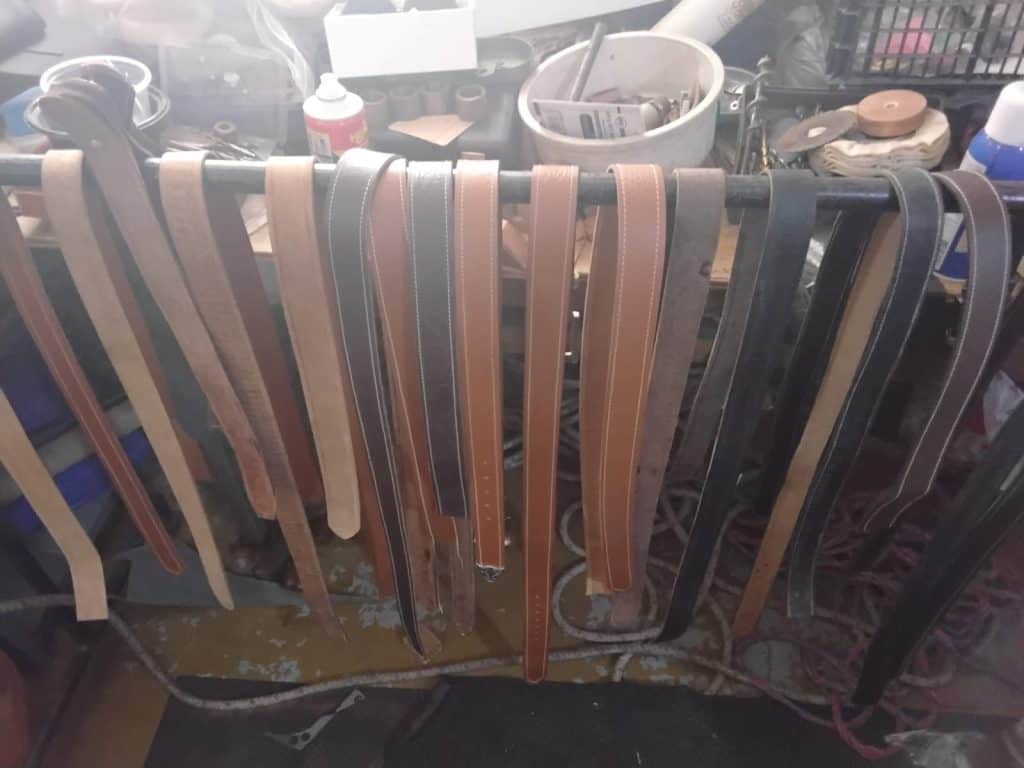 Cueros y cinturones de piel en proceso de fabricación en un taller artesanal de marroquinería. Materiales y herramientas para crear accesorios de cuero personalizados y de alta calidad, en un entorno de trabajo artesanal. – SoyMigrante.com REVISTA