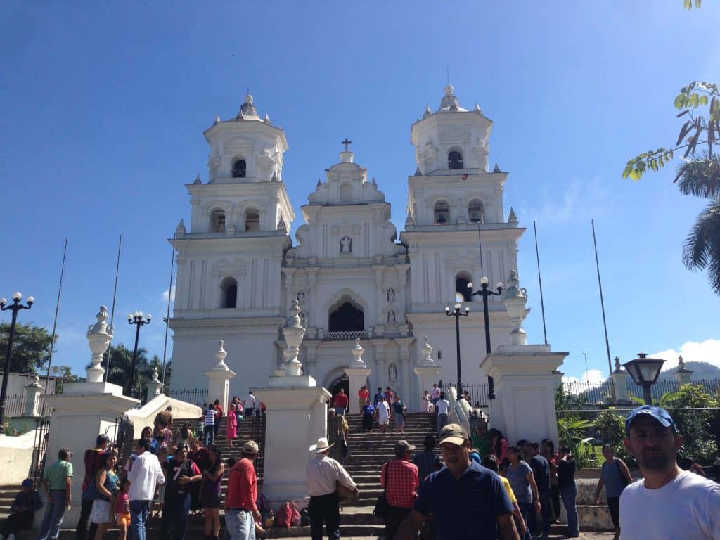 Imponente iglesia colonial blanca en una pintoresca ciudad mexicana, rodeada de turistas y locales disfrutando de la arquitectura y cultura local. – SoyMigrante.com REVISTA