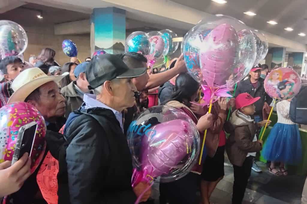 Personas en un evento con globos de corazón de personajes de dibujos animados y figuras de colores, en un ambiente social y festivo, promoviendo la migración y comunidad en México. – SoyMigrante.com REVISTA