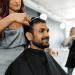 Barbero cortando el cabello a un cliente masculino en un salón de belleza moderno, cuidado y relajado. Imagen ilustrativa de servicios de barbería y peluquería para artículos de revistas sobre estilo y cuidado personal.