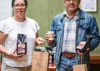 Artesanos con productos de café en una feria, promoviendo la cultura migrante y el comercio justo en la revista SoyMigrante.com REVISTA.