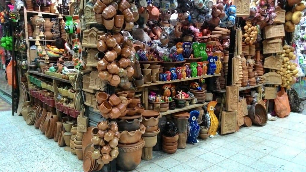 Colorido puesto de artesanías y objetos de cerámica y barro en una tienda de mercado en México. Decoraciones, figuras y vasijas de cerámica en diferentes formas y colores, ideales para decoración y regalos. – SoyMigrante.com REVISTA