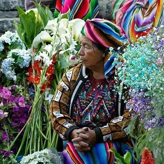 Flores y mujer indígena con vestido colorido en mercado tradicional en México, cultura originaria, artesanías mexicanas, comunidad indígena, tradición y costumbres mexicanas. – SoyMigrante.com REVISTA