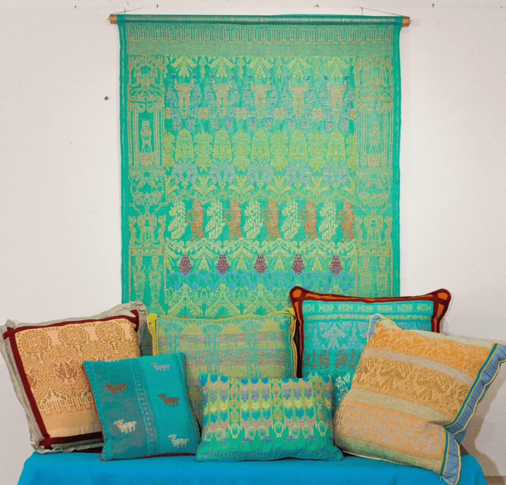 Telas y cojines artesanales con diseños tradicionales y coloridos. Artesanía textil mexicana exhibida en una muestra cultural, resaltando la riqueza de la cultura popular y las técnicas ancestrales.