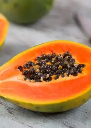 Jugosidad de papaya con semillas negras en una mesa de madera natural, saludable y nutritiva, ideal para quienes valoran la alimentación natural y el bienestar, promoción de recetas y beneficios de frutas tropicales.