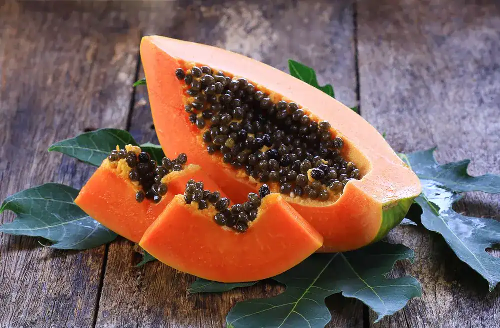 Jugo de papaya con semillas negras, fruta tropical saludable y refrescante sobre mesa de madera rústica. – SoyMigrante.com REVISTA