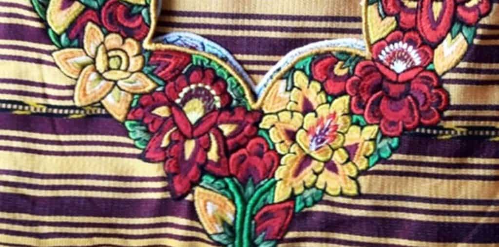 Colorido bordado de flores tradicionales mexicanas, representando la riqueza cultural y artística en la revista SoyMigrante.com REVISTA. Diseño vibrante que resalta el folclore y la identidad mexicana en el contexto migratorio.