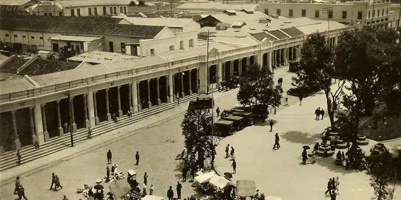 Calle histórica en una ciudad antigua con tiendas y comerciantes, representando el patrimonio cultural y la vida cotidiana en un entorno clásico. – SoyMigrante.com REVISTA