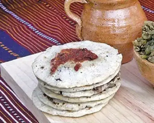 Pan de maíz tradicional con salsas mexicanas en un entorno cultural colorido y auténtico.