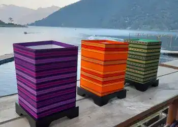 Coloridos maceteros de diseño en un entorno con vista a un lago y montañas durante el atardecer, ideal para artículos sobre cultura y arte en México.