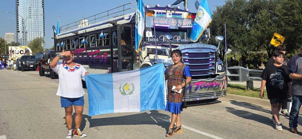 Susana Oxlaj, de azul, junto al emblemático autobús de taquería Mi Pueblito, que pertenece también a connacionales radicados en Houston, Texas, durante el desfile conmemorativo de fiestas patrias, en el cual participaron también mexicanos y centroamericanos. (Foto cortesía Chapines de Corazón Houston) – SoyMigrante.com REVISTA