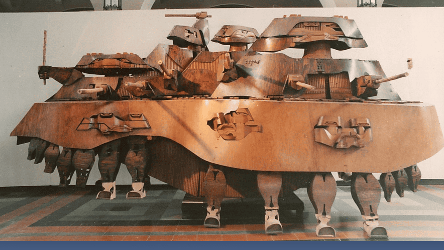 Música Grande es una escultura en madera de Efraín Recinos que representa una marimba y a la vez una fortaleza. Se puede imaginar que avanza, camina y suena sin parar. Está en el Museo Nacional de Arte Moderno de Guatemala. – SoyMigrante.com REVISTA