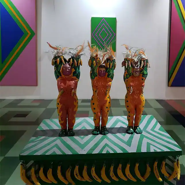 Coloridas esculturas de personajes con disfraces de animales, exhibidas en una galería de arte con fondos geométricos y vibrantes, en un ambiente contemporáneo y artístico.