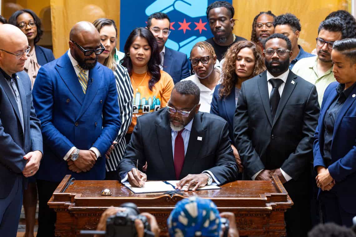 Momento en el que se oficializa la nueva política de la ciudad de Chicago para evitar incidentes de redadas en áreas municipales. El alcalde Michael Johnson firma la orden ejecutiva denominada ICE Free Zones – SoyMigrante.com REVISTA