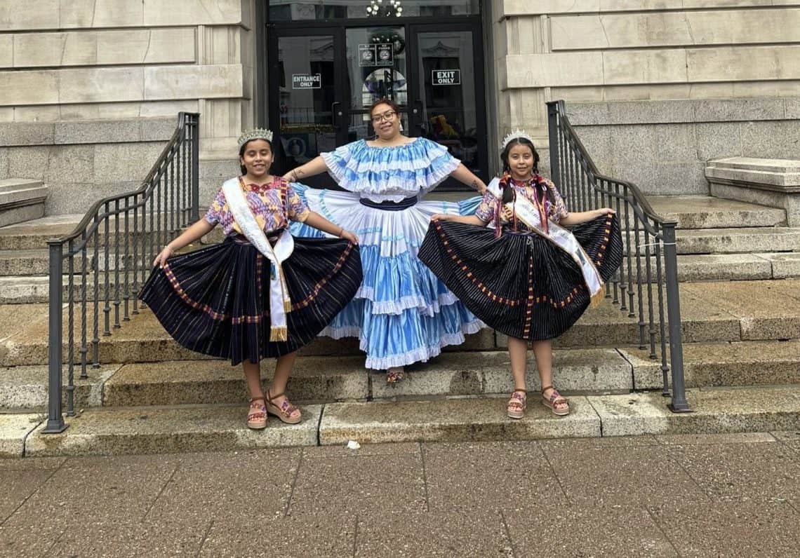 Martha Francisca Coc inculca en sus hijas el amor a la cultura guatemalteca y por supuesto ellas ya le ayudan también en la preparación del fiambre, para prolongar la tradición así como ella alguna vez la aprendió. Fotografía durante la ceremonia patria en Patterson, New Jersey en septiembre 2025. (Foto cortesía Martha Coc) – SoyMigrante.com REVISTA