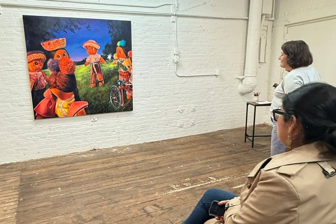 La directora del Guatemalan Center of New England, Tiana Ochoa, admira una de las pinturas de Dominick Cocozza, artista originario de Mazatenango y adoptado por estadounidenses cuando tenía un año de edad. (Fotografía Nacho Méndez) – SoyMigrante.com REVISTA