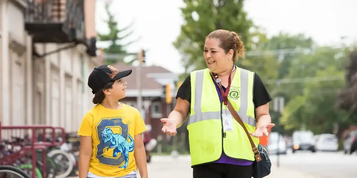 Silvia Consuelo Morán, migrante guatemalteca en Cicero, Chicago, se involucra en voluntariado y servicio a la comunidad. En esta imagen participa en actividades de seguridad escolar y posa para la foto junto a su hijo menor. – SoyMigrante.com REVISTA