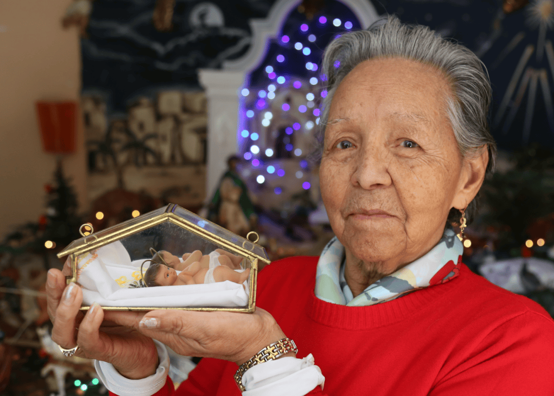 Olga de Donis se siente agradecida por las bendiciones recibidas a lo largo de su vida familiar, como migrantes guatemaltecos en Estados Unidos y ahora en su tierra natal. Poseen un Niño Jesús muy antiguo, que es un tesoro familiar (Foto Edwin O. Castro) – SoyMigrante.com REVISTA