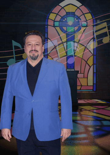 Man in a blue blazer posing in front of a colorful stained-glass backdrop with musical notes and stage lighting.