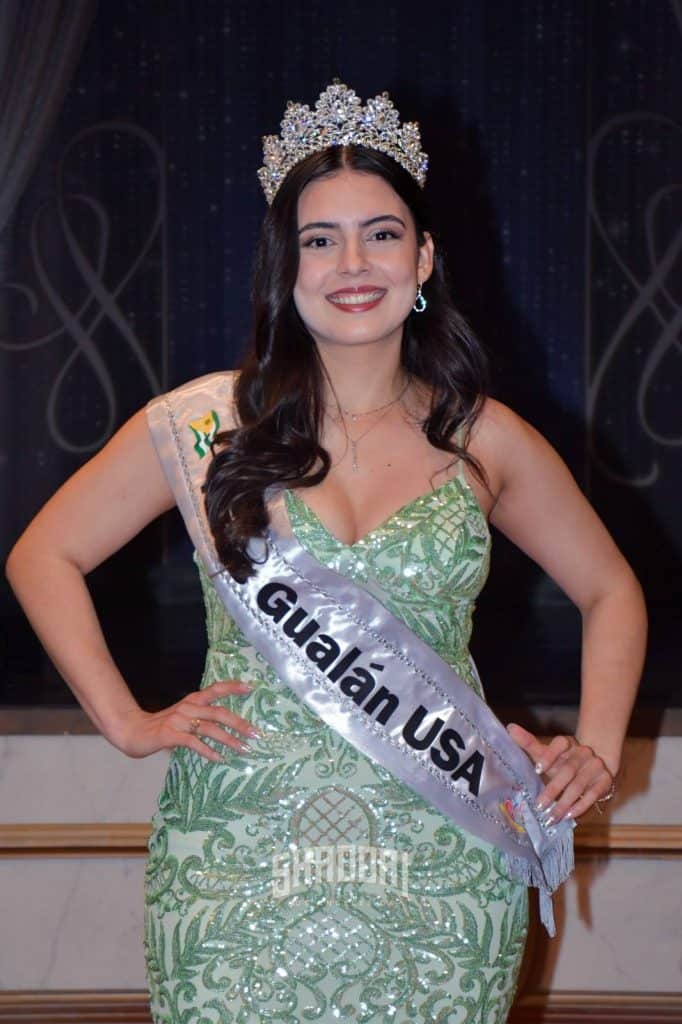 Pageant winner wearing a jeweled crown and a light green sequined gown, sash reading 'Guadalain USA' and a smile.