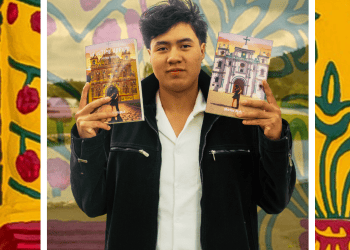 Young man in a black jacket holds up two illustrated brochures in front of a colorful mural background.