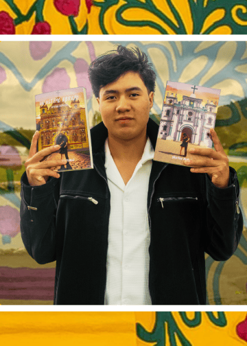 Young man in a black jacket holds up two illustrated brochures in front of a colorful mural background.