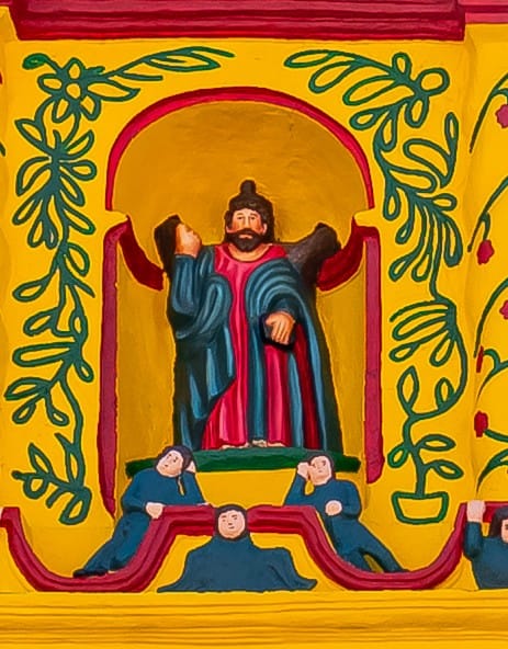 Según la tradición cristiana, San Andrés Apóstol, patrono del pueblo de Xecul, fue martirizado crucificado en una cruz en forma de X. A su lado está la corona de la gloria por su santidad.