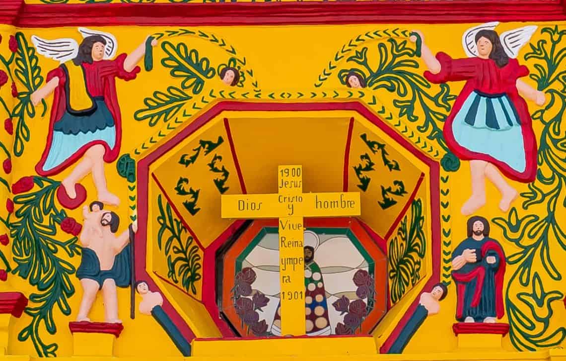 Arcángeles Rafael, a la derecha y Uriel a la izquierda. Reverencian la Santa Cruz de Jesús, rodeada de decoraciones de hojas de Pacaya. Los santos en la parte inferior son San Cristóbal y San Juan.