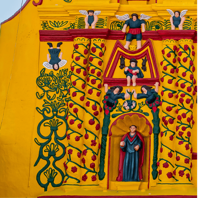 En la hornacina está San Pablo apóstol, flanqueado por ángeles con zancos que cuidan el grano del sagrado maiz. Sentado con la guitarra está Hun Chouen, hermano de HunBatz, ambos protectores de los artistas y los músicos. Sentado con las alas abiertas está Ixbalanqué, el otro gemelo prodigioso del Popol Vuh. Las columnas con enredaderas de mora evocan la bendición del alimento que provee la tierra. Encima de las hojas de pacaya está, de cabeza, el ángel caído.
