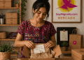 Woman in a colorful patterned dress unpacks a gift box with a tied paper wrapping and a handwritten note reading '¡Gracias por apoyar mi sueño!' in a craft shop with shelves and plants behind her.