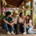 Group of friends or family sitting together on a rustic wooden porch, smiling and chatting outdoors.