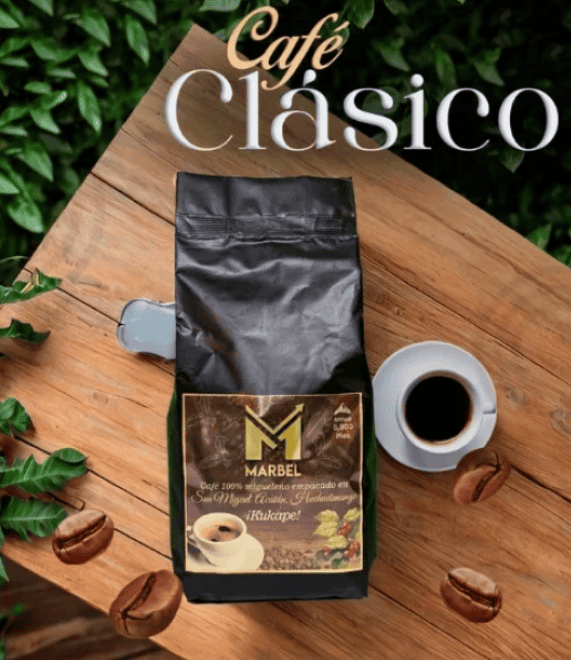 Bag of Café Clásico coffee on a wooden table with a cup of black coffee and scattered coffee beans, outdoors with greenery in the background.