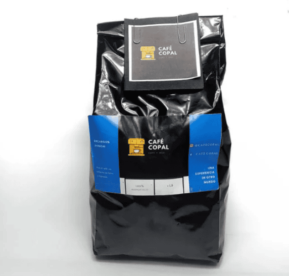 Black coffee bag with a blue wraparound label reading Café Copal and a small top-tag box attached.