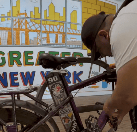 Así llega el guatemalteco Gustavo Ajché, trabajador de entregas o delivery, a dejar su bicicleta en la exposición Moma PS1 como parte de una instalación en la cual le pagan por el tiempo que está en exhibición para representar la importantre labor de este sector de trabajadores.