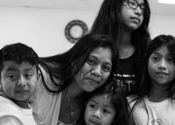 Mother with four children posing closely for a family portrait indoors (black and white).**
