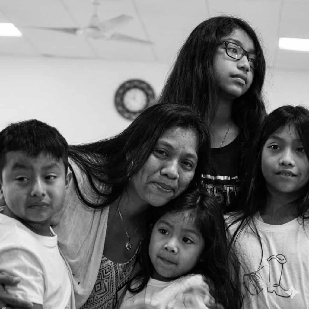 Mother with four children posing closely for a family portrait indoors (black and white).**