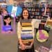Smiling woman in a bookstore holding a tall stack of colorful books, with decorative cartoon overlays (heart, girl, bird) in the foreground.