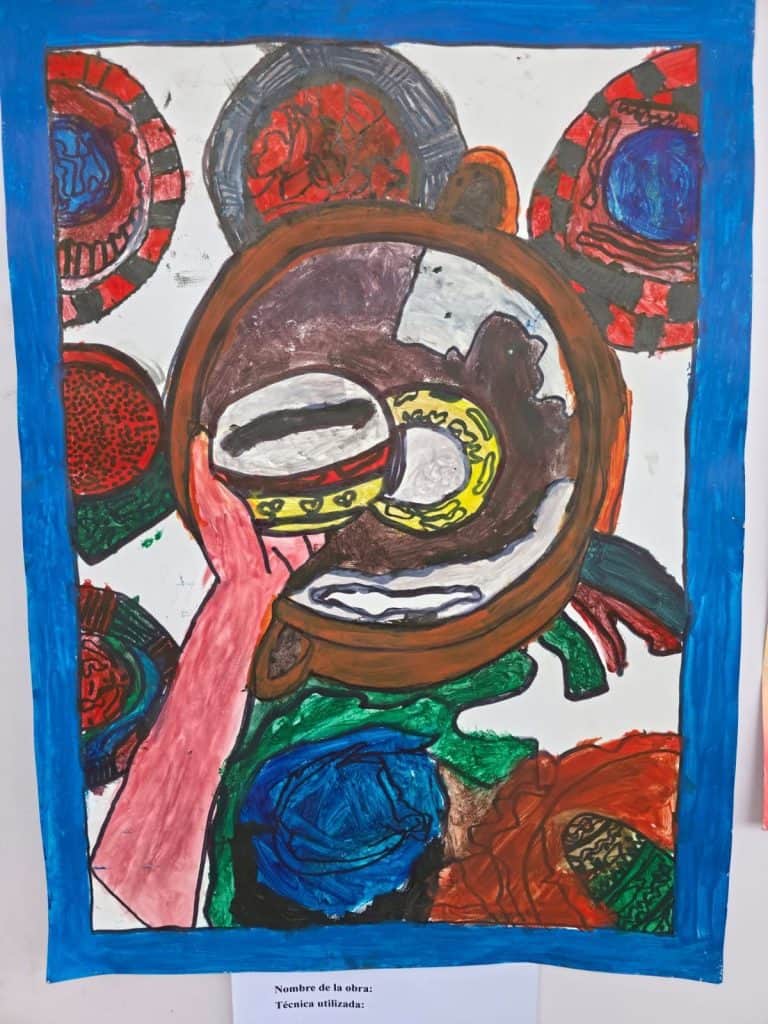Abstract painting with a large brown circular ring at the center, a pink hand reaching toward the ring, and colorful circular patterns around it inside a blue frame.