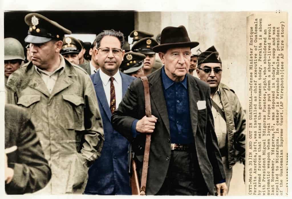 Fotografía histórica de 1960, cuando el general Miguel Ydígoras Fuentes era presidente. Lleva una subametralladora al hombro y camina junto al coronel Enrique Peralta Azurdia, Ministro de Defensa. La imagen corresponde al combate de la rebelión de algunos oficiales del Ejército que intentaron dar un Golpe de Estado el 13 de noviembre de 1960. El 31 de marzo de 1963, Peralta dio el Golpe al mandatario. – SoyMigrante.com REVISTA – SoyMigrante.com REVISTA Fotografía histórica de 1960, cuando el general Miguel Ydígoras Fuentes era presidente. Lleva una subametralladora al hombro y camina junto al coronel Enrique Peralta Azurdia, Ministro de Defensa. La imagen corresponde al combate de la rebelión de algunos oficiales del Ejército que intentaron dar un Golpe de Estado el 13 de noviembre de 1960. El 31 de marzo de 1963, Peralta dio el Golpe al mandatario.