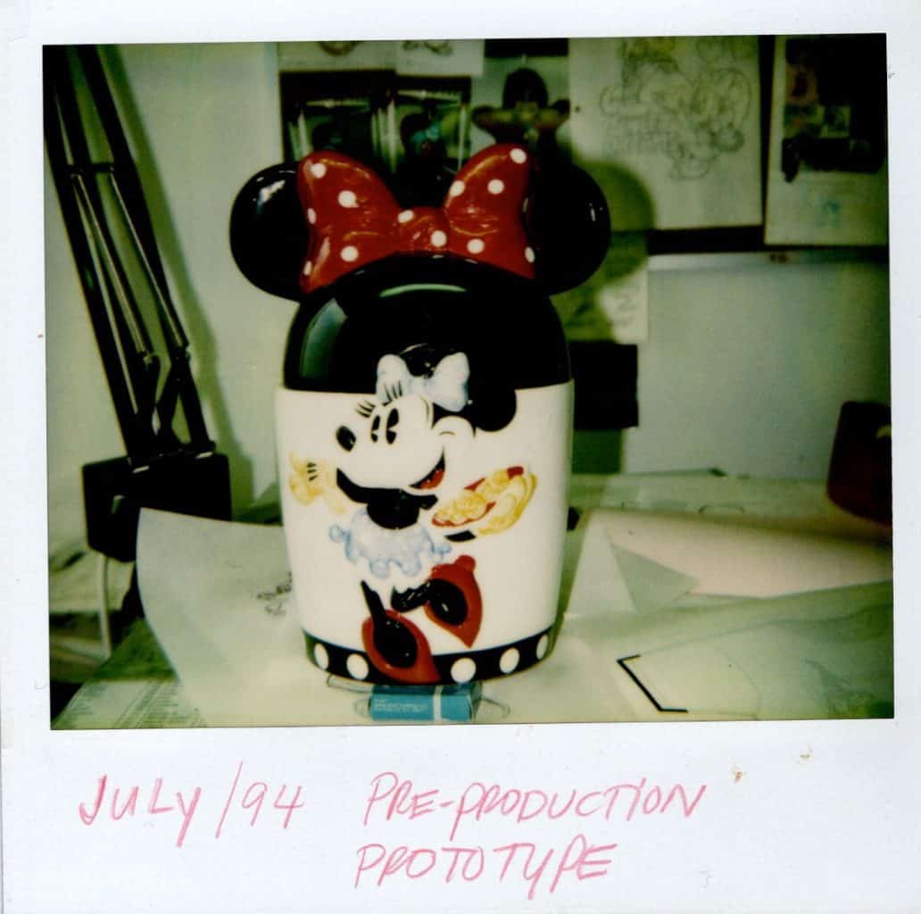 Pre-production prototype of a Minnie Mouse ceramic cookie jar with a red polka-dot bow, shown on a desk.