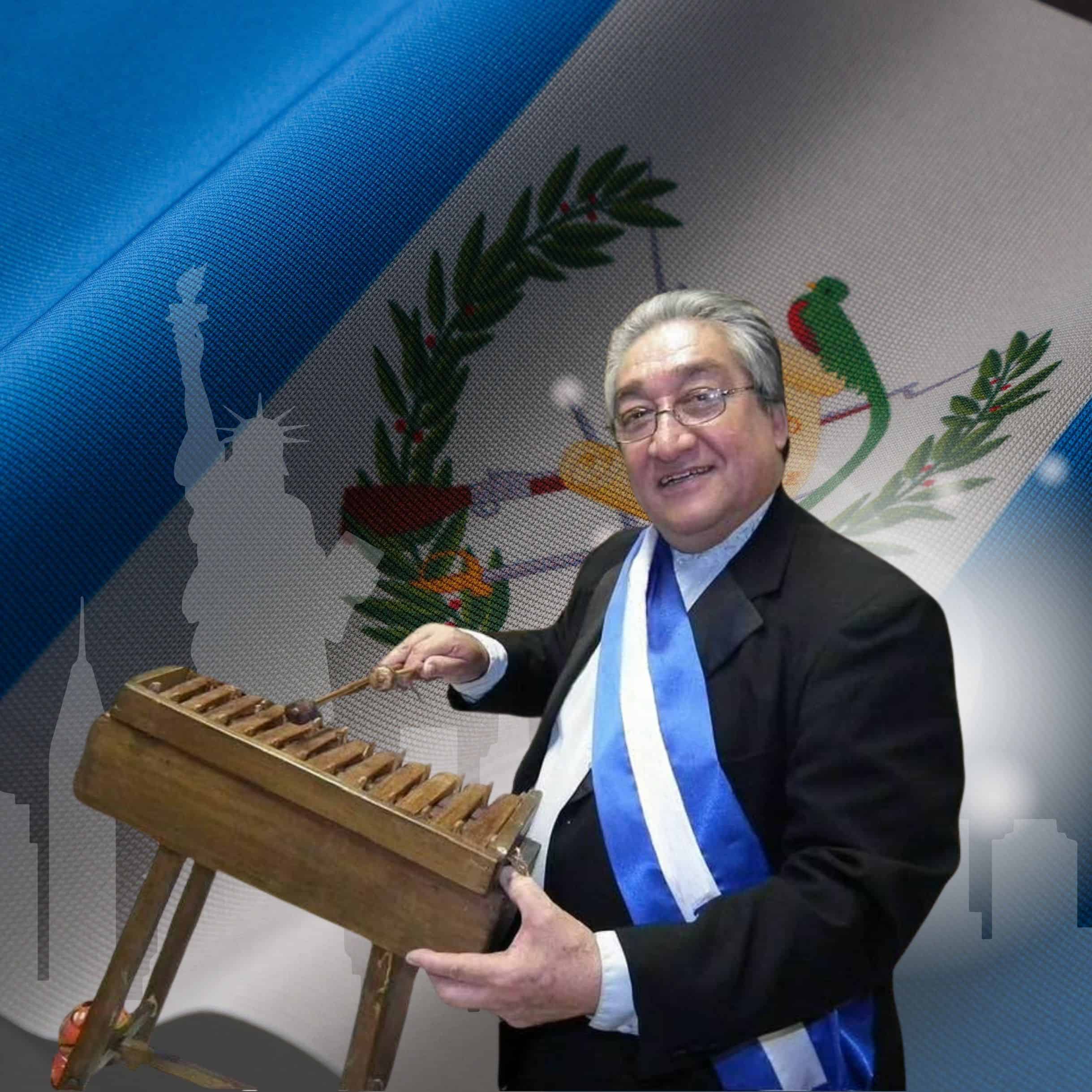 david marin el chapin locutor guatemalteco fallecido en nueva york – SoyMigrante.com REVISTA Older man in a suit wearing a blue-and-white ceremonial sash plays a wooden xylophone on a decorated backdrop.