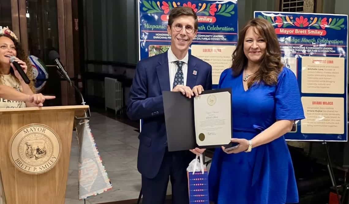 El alcalde de Providence, Brett Smiley entrega a la emprendedora guatemalteca Eberly Oliva, un reconocimiento por sus aportes a la comunidad, como parte de las actividades por el Mes de la Herencia Hispana 2026