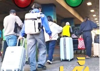 equipaje exento impuestos articulos pago regalos viajeros migrantes – SoyMigrante.com REVISTA Group of travelers with rolling suitcases waiting in line at airport security checkpoint in a busy terminal.