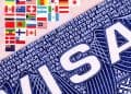 Close-up of a large blue 'USA' graphic with a row of small international flags above it on a pink background.